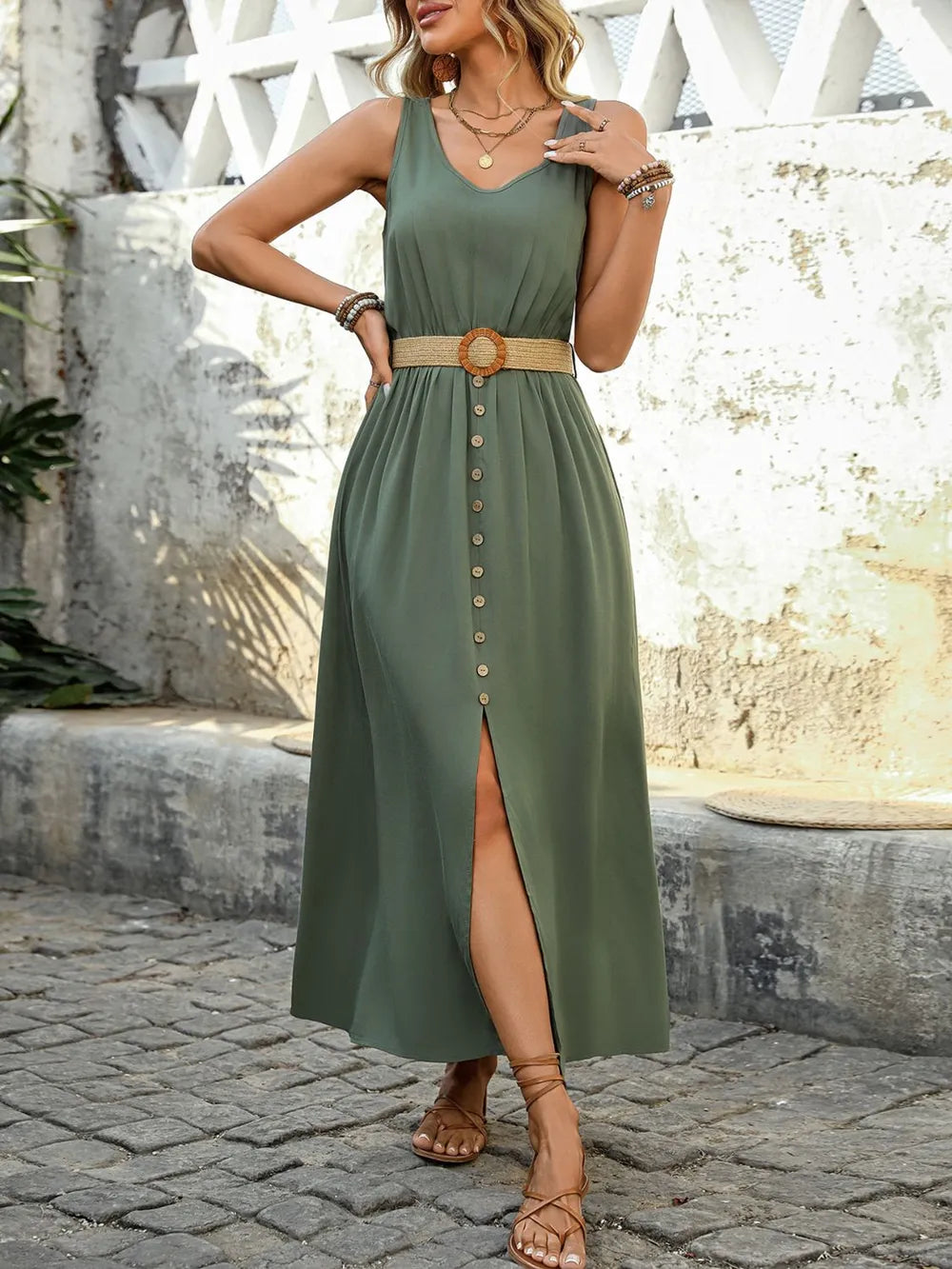 Woman wearing a green dress with a belt, standing on a stone path.