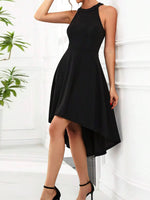 Black dress worn by a person against a white wall with a plant in the background