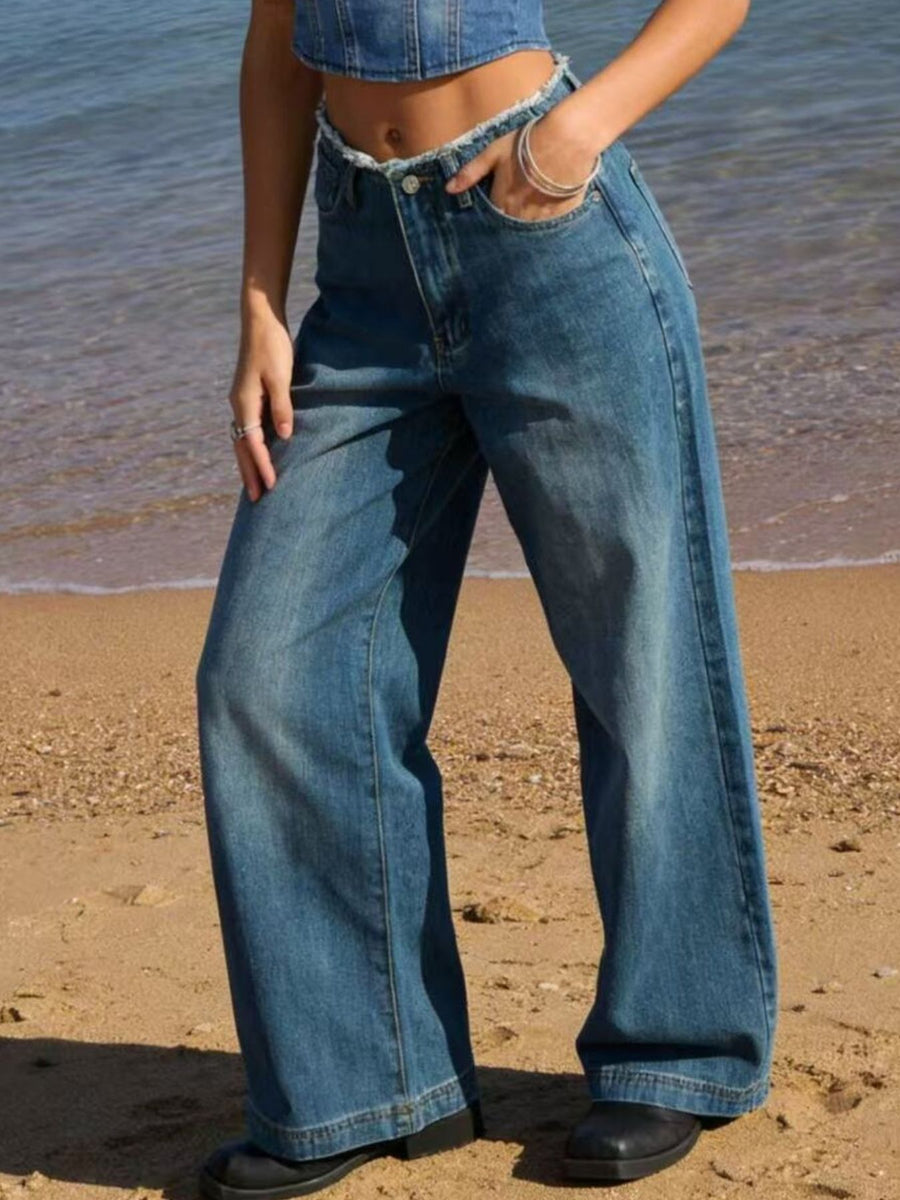 Person wearing blue jeans standing on a beach