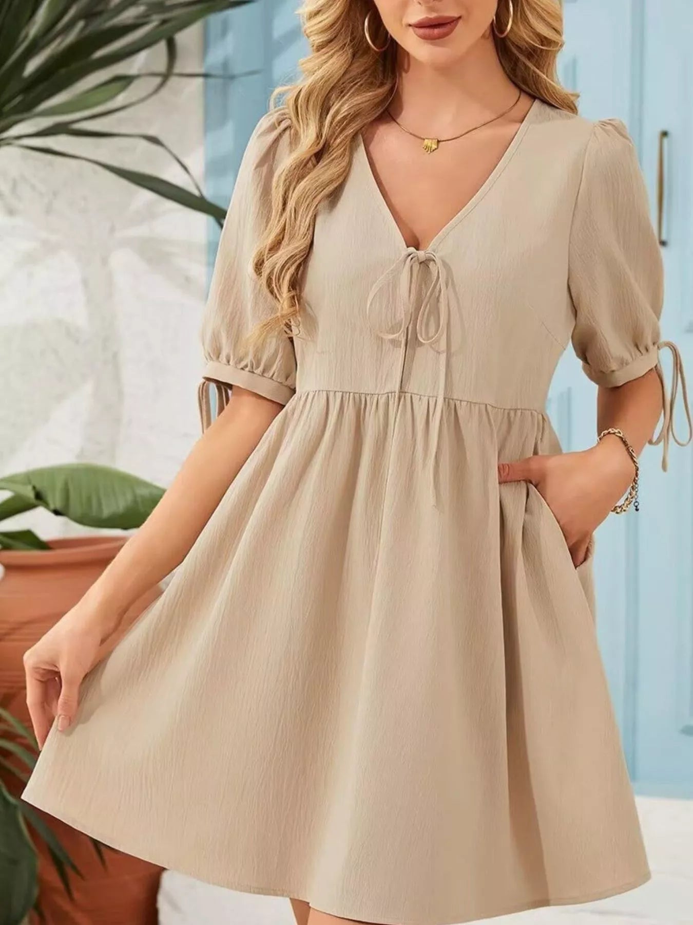 Woman wearing a beige dress with a blurred indoor background