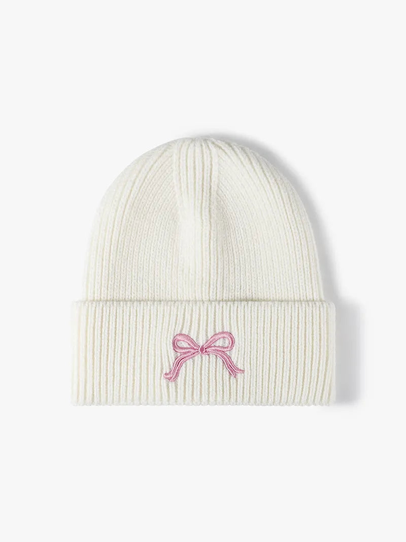 White beanie with a pink bow design on a white background