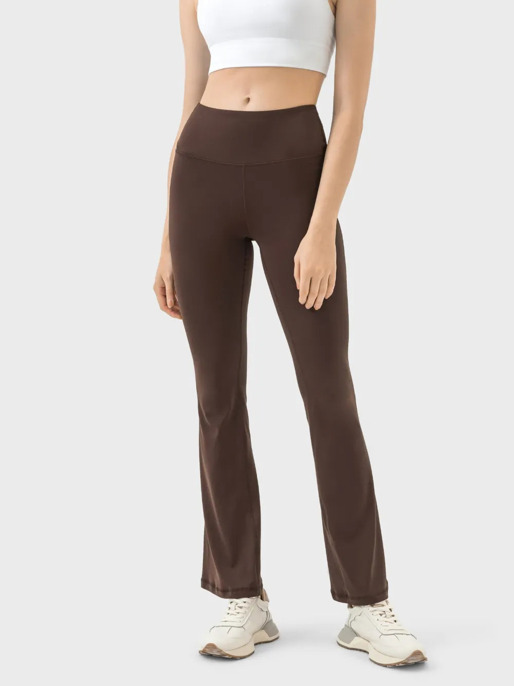 Person wearing brown high-waisted leggings on a white background