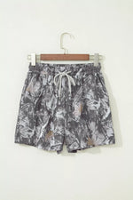 Camouflage-patterned shorts on a hanger against a white background
