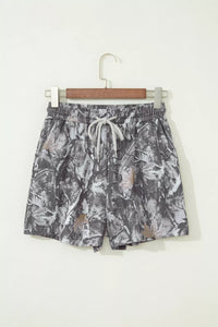 Camouflage-patterned shorts on a hanger against a white background