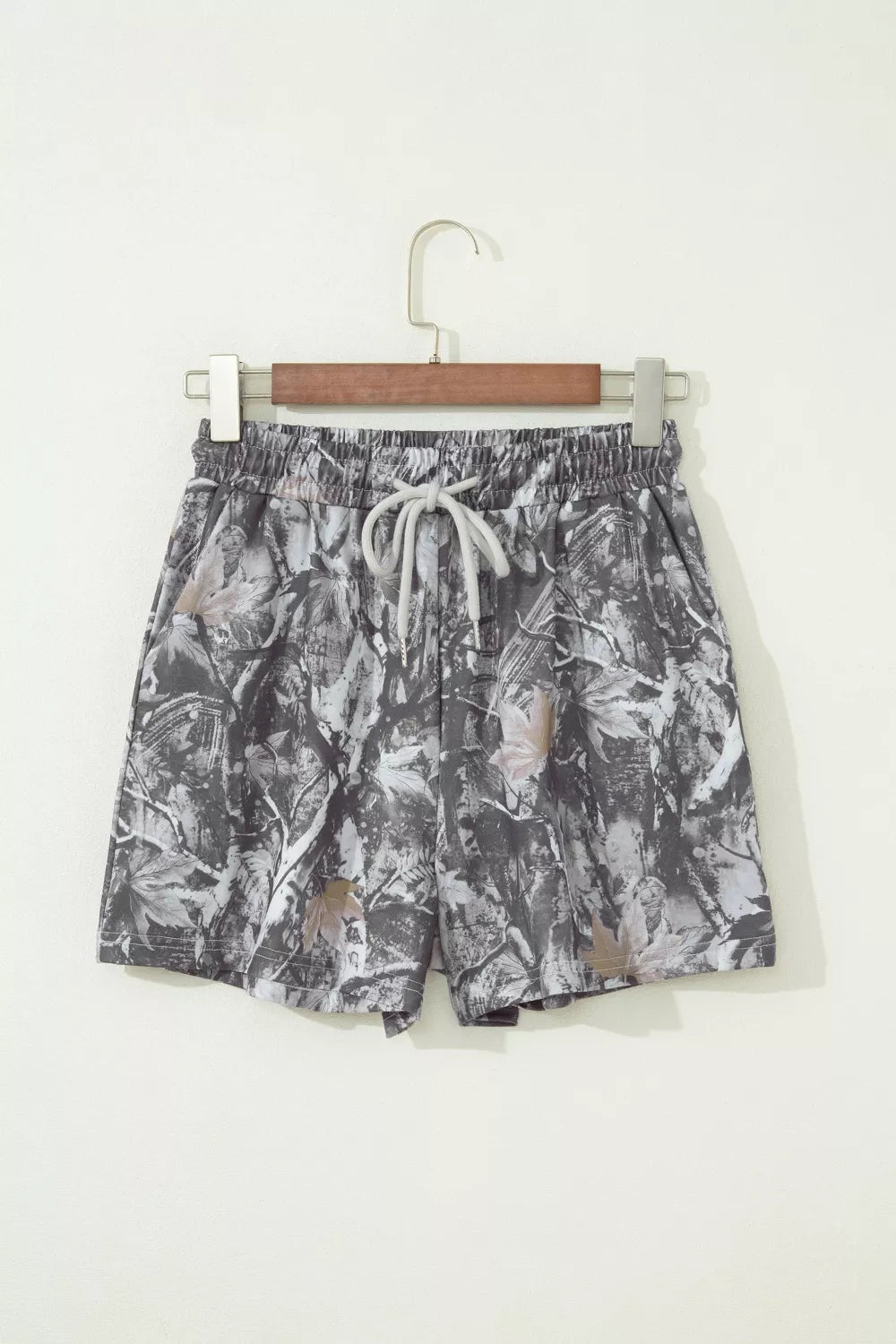 Camouflage-patterned shorts on a hanger against a white background