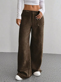 Person wearing brown corduroy wide-leg pants on a plain background