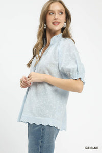 Woman wearing an ice blue blouse with scalloped hem on a white background
