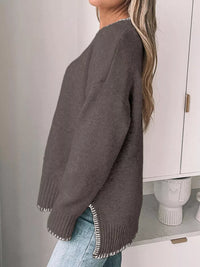 Person wearing a brown sweater with white trim in a minimal indoor setting