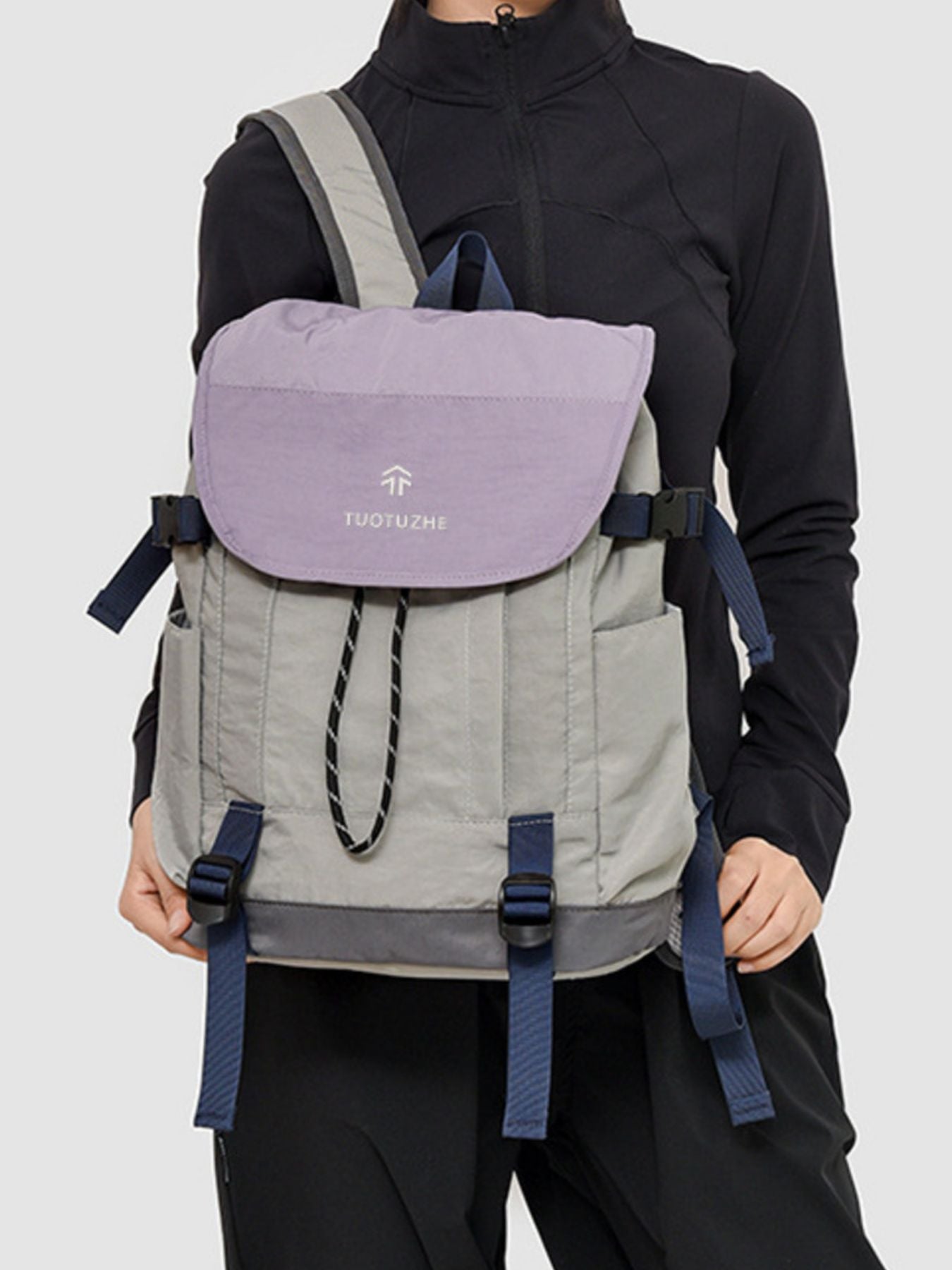 Person wearing a gray and purple backpack with 'Tudor One' branding on a light gray background