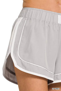 Light grey athletic shorts with white trim on a white background