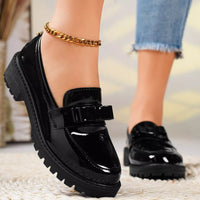 Black shiny shoes with a gold chain on a blurred background