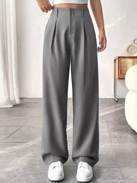 Person wearing gray wide-leg pants in a minimalistic room.