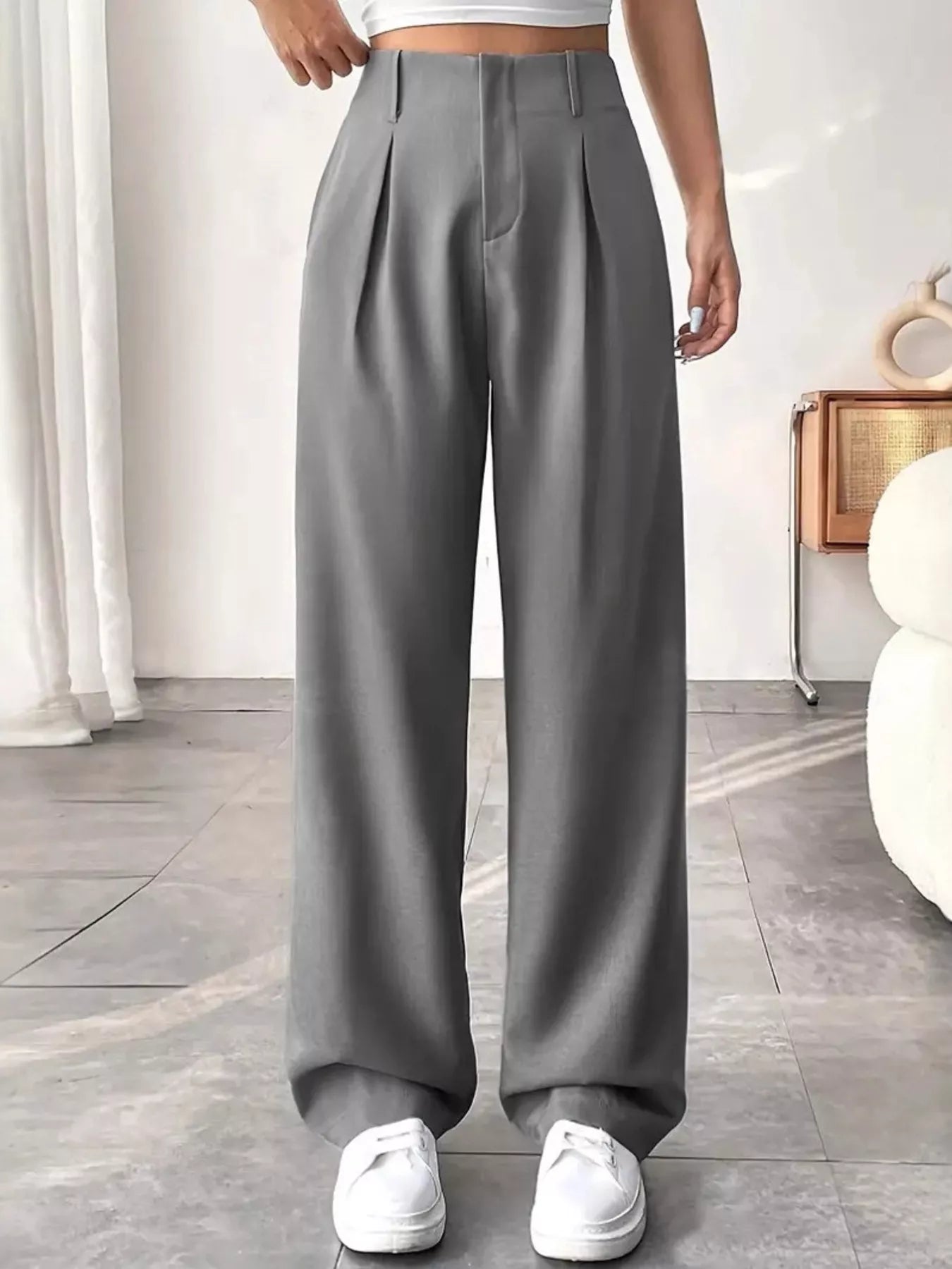 Person wearing gray wide-leg pants in a minimalistic room.