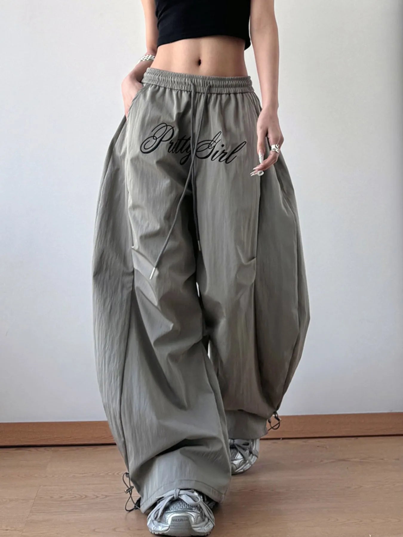 Person wearing gray baggy pants with 'Bella Girl' text, standing against a plain background.