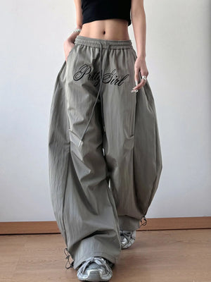 Person wearing gray baggy pants with 'Bella Girl' text, standing against a plain background.