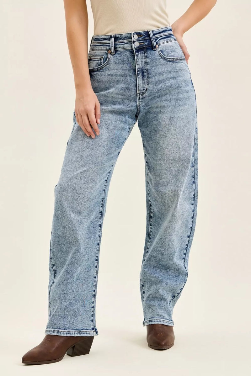 Person wearing light blue jeans on a beige background