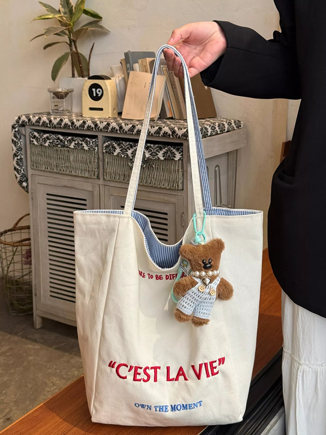 Woman holding Cute shoulder bag with a small teddy bear attached to it