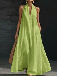 Woman wearing a bright green halter neck dress against a dark background