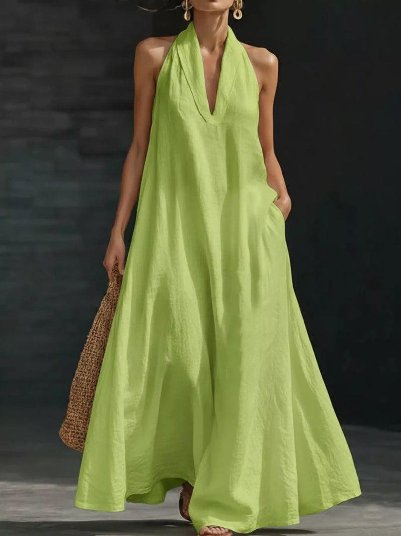 Woman wearing a bright green halter neck dress against a dark background