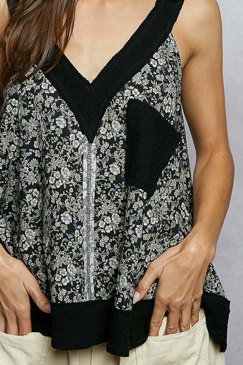 Woman wearing a floral top with black accents on a plain background