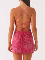 Pink dress with intricate detailing and criss-cross straps on a white background
