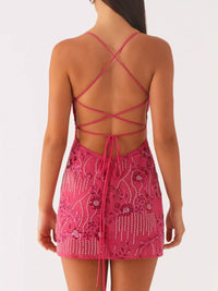 Pink dress with intricate detailing and criss-cross straps on a white background