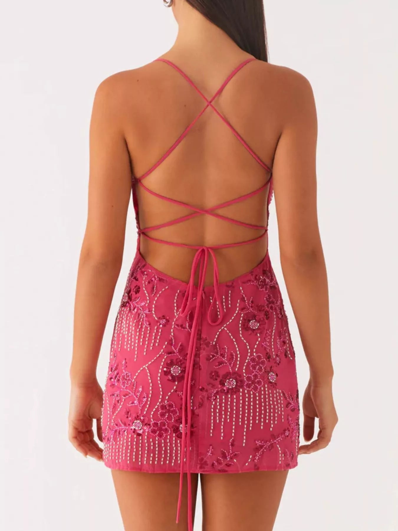 Pink dress with intricate detailing and criss-cross straps on a white background