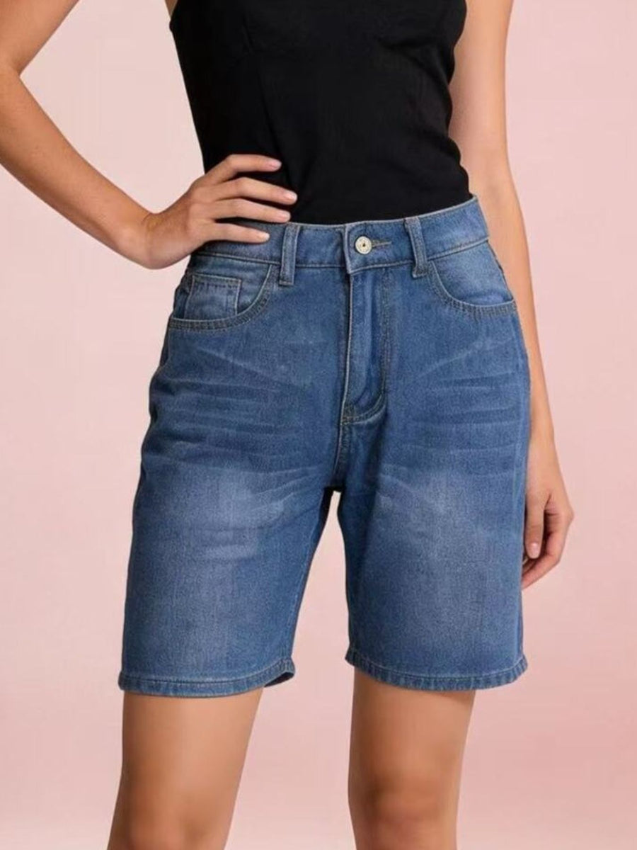 Person wearing blue denim shorts on a pink background