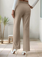 Beige wide-leg pants worn by a person indoors with a neutral background