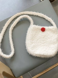White textured handbag with a red button on a light gray surface