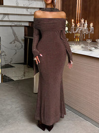 Woman in a brown off-shoulder dress standing in an elegant interior setting.