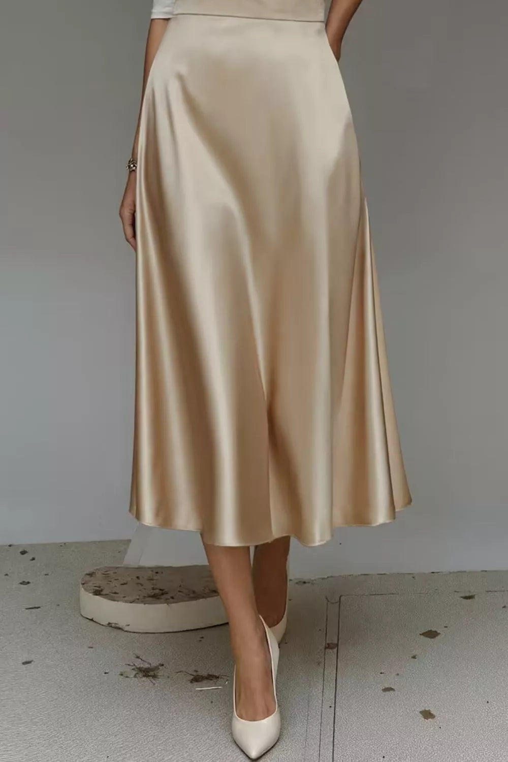 Beige satin skirt worn by a person on a plain background