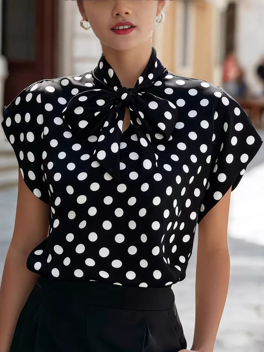 Woman wearing a black polka dot blouse with a blurred background