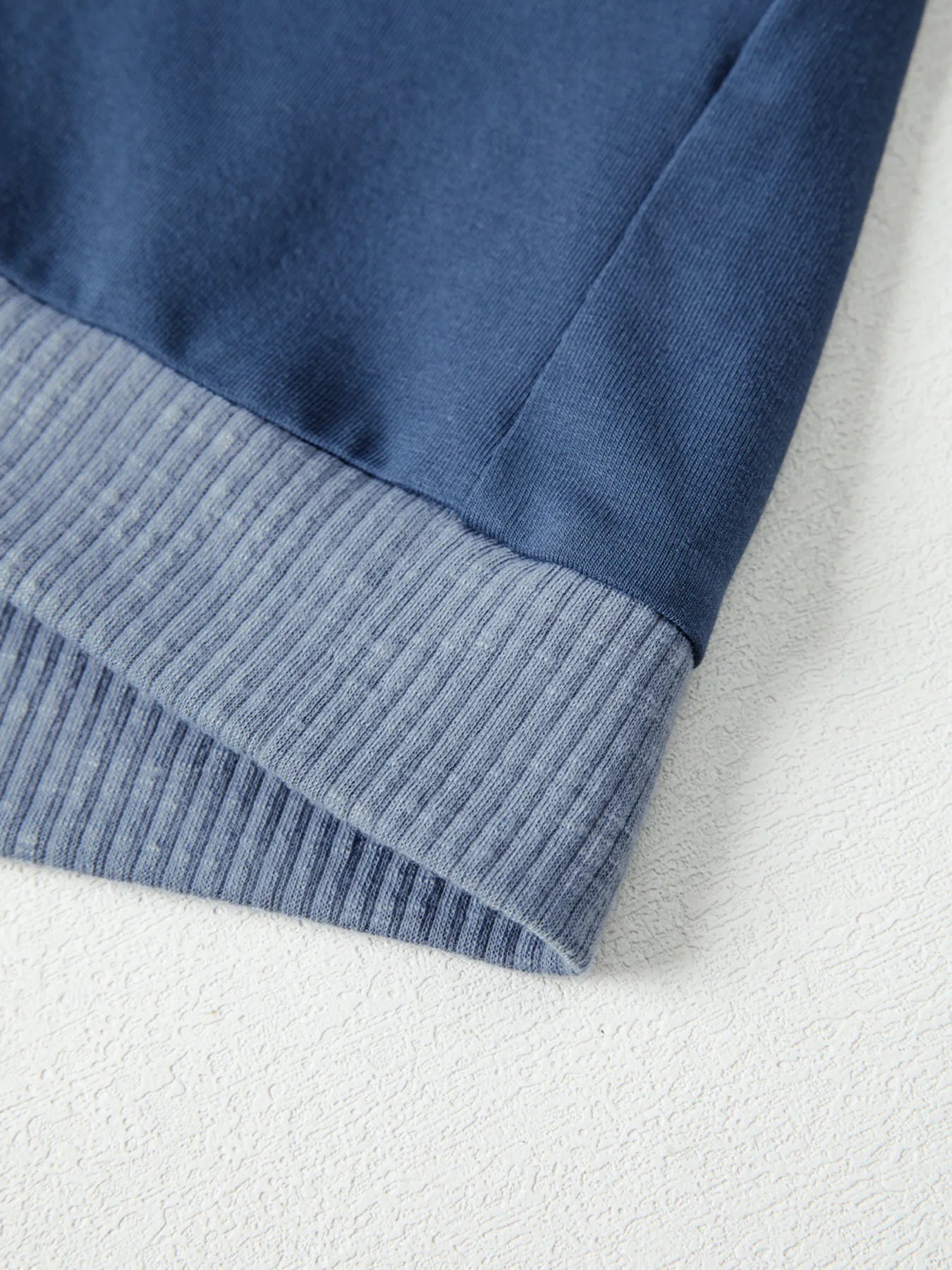 Close-up of a blue fabric with ribbed trim on a white background