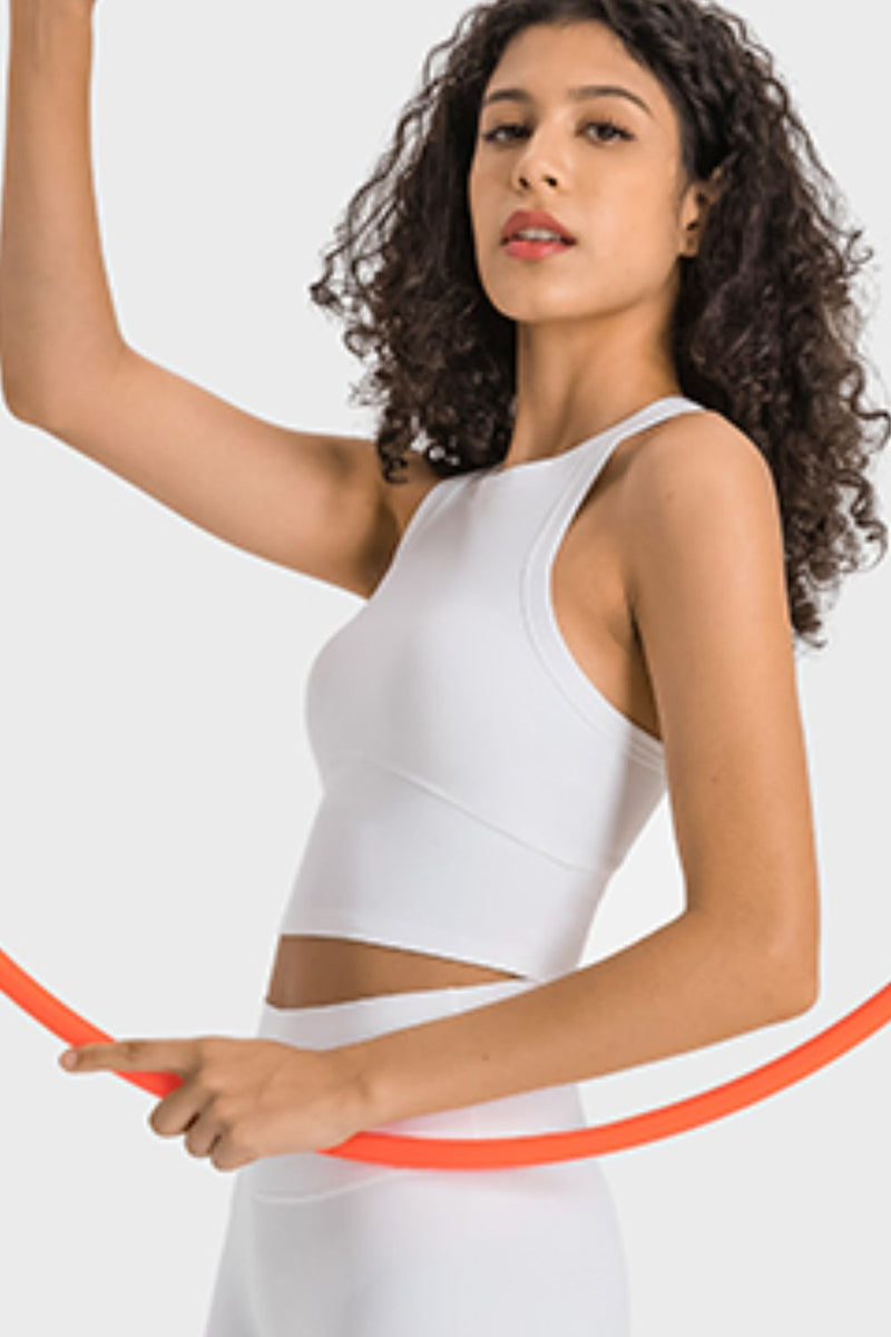 Woman in a white sleeveless top holding an orange hoop against a light gray background