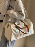 Person holding a beige bag with colorful cat illustrations against a neutral background
