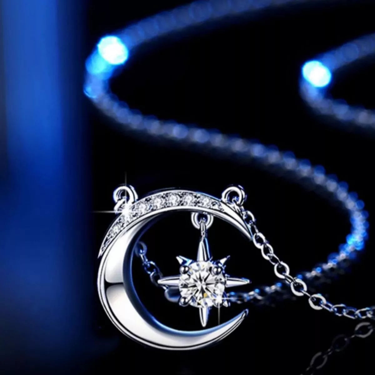 Silver necklace with moon and star pendant on a dark background