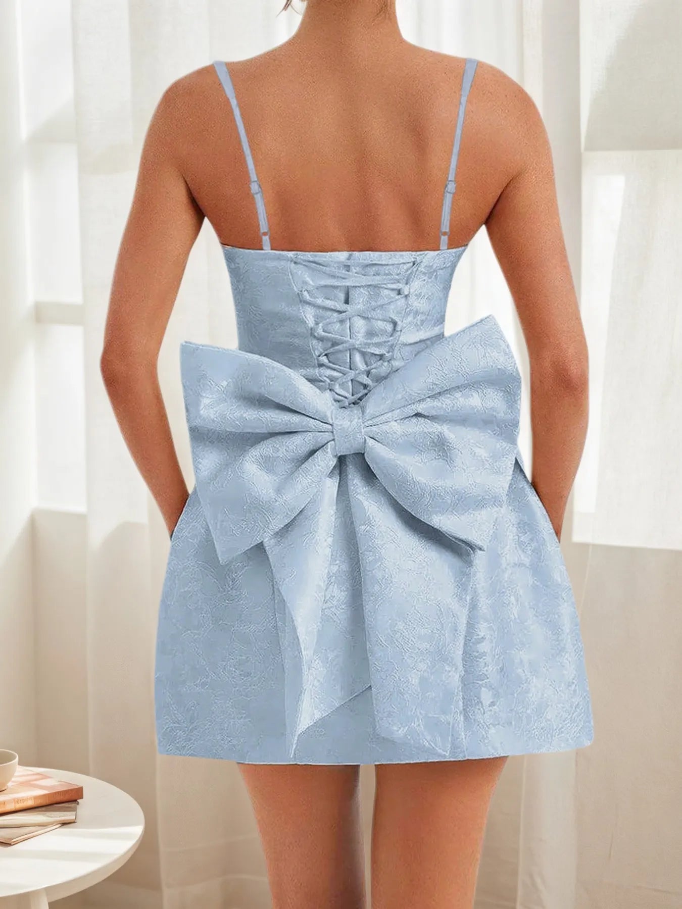 Light blue dress with a large bow detail on the back, worn by a person.