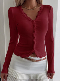 Red long-sleeve top with ruffled details worn by a person on a white background