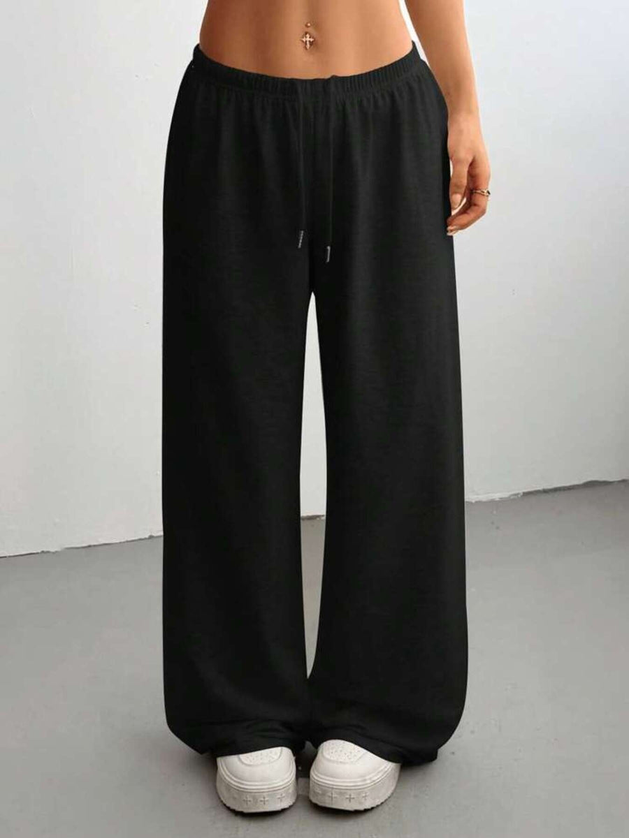Person wearing black wide-leg pants against a white background