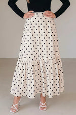 Person wearing a polka dot skirt with a plain background