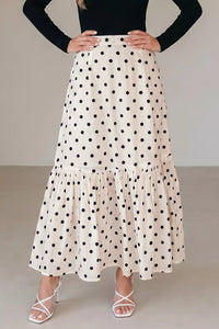 Person wearing a polka dot skirt with a plain background