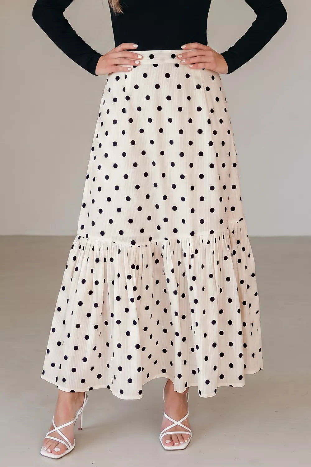 Person wearing a polka dot skirt with a plain background