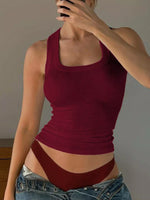 Person wearing a red tank top and denim shorts against a plain background