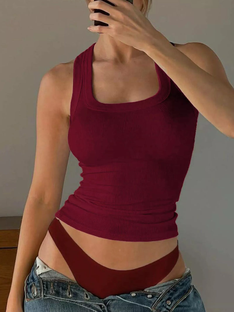 Person wearing a red tank top and denim shorts against a plain background