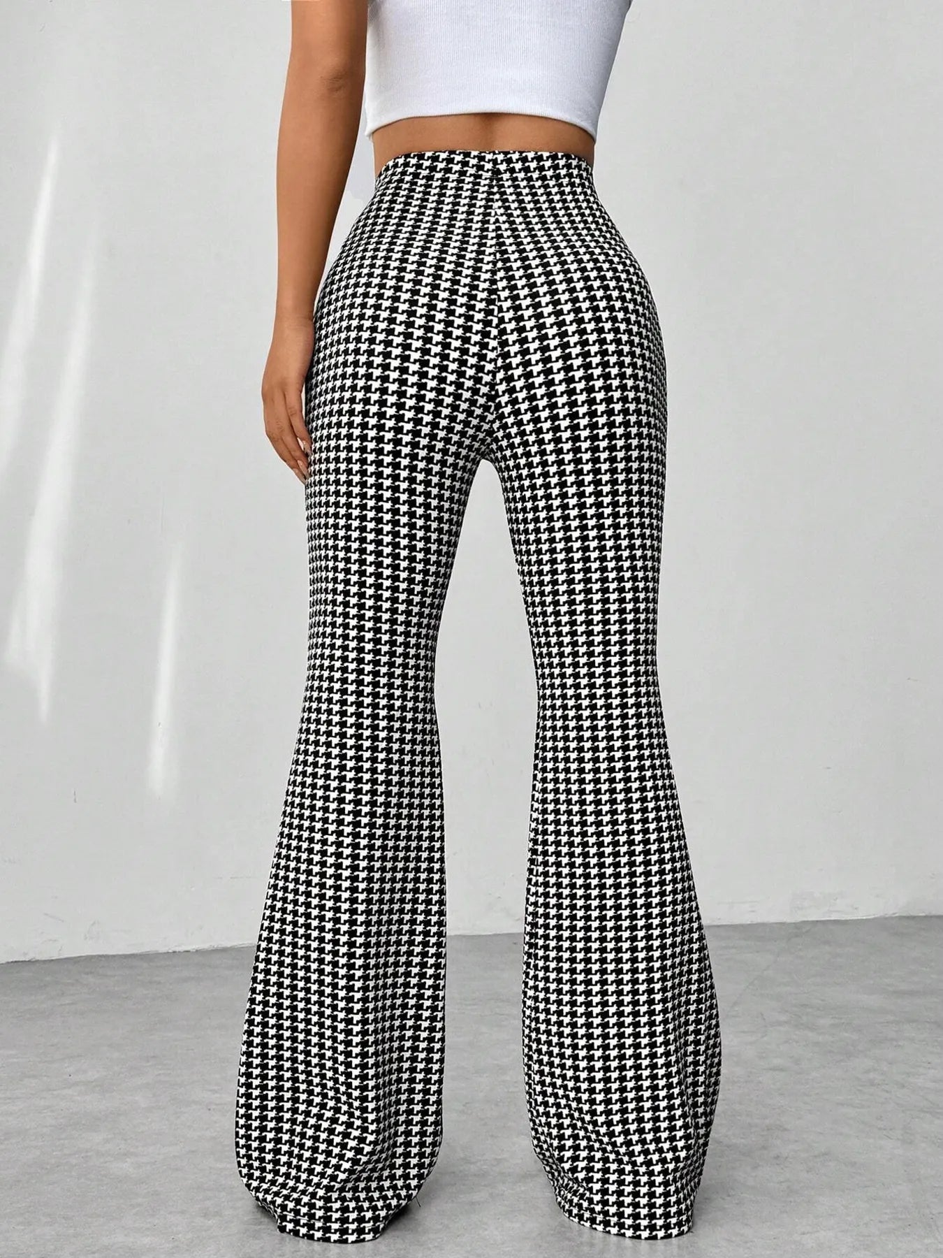 Houndstooth patterned pants worn by a person on a plain background
