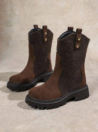 Pair of brown suede boots with black soles on a beige background