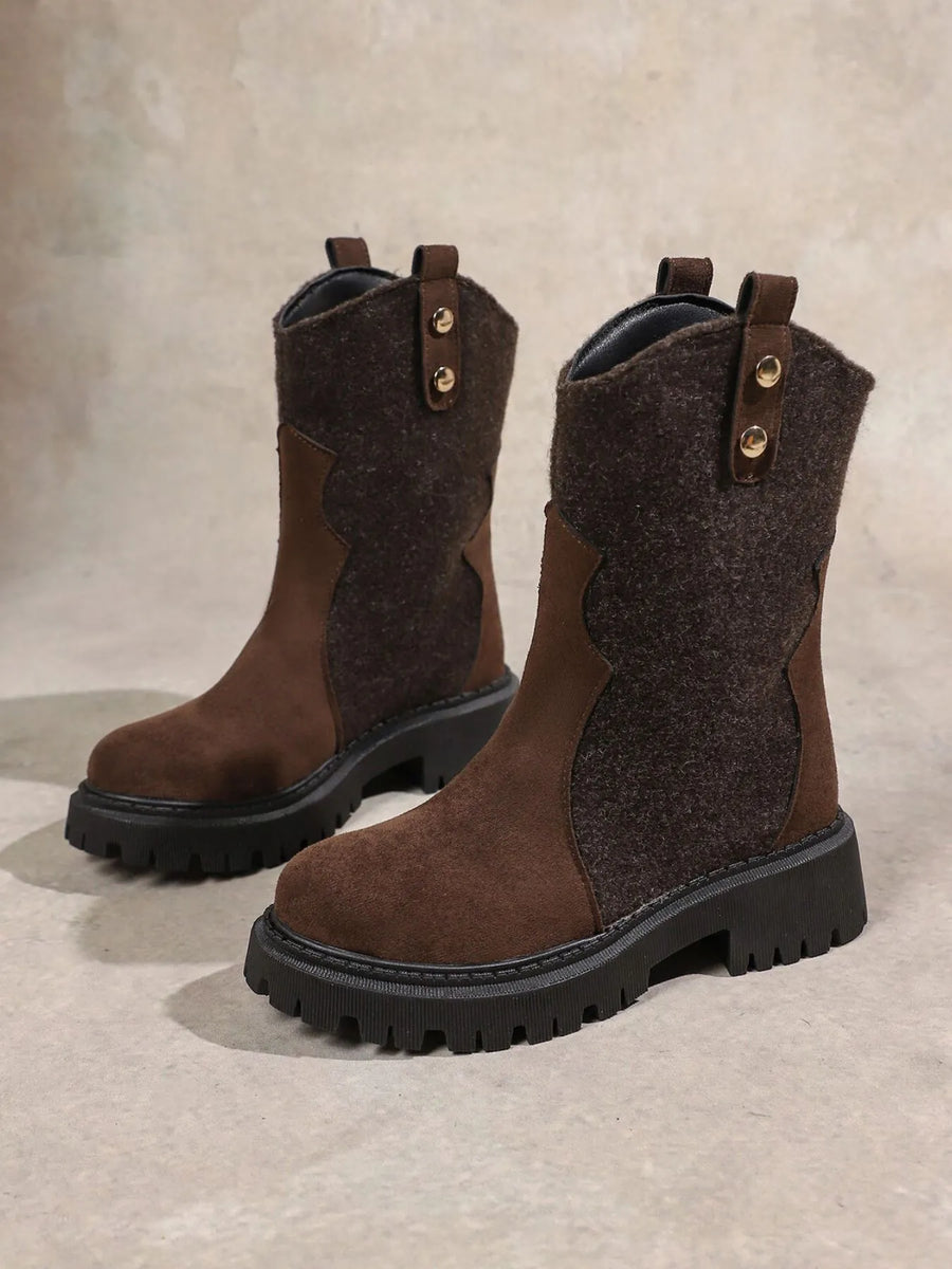 Pair of brown suede boots with black soles on a beige background