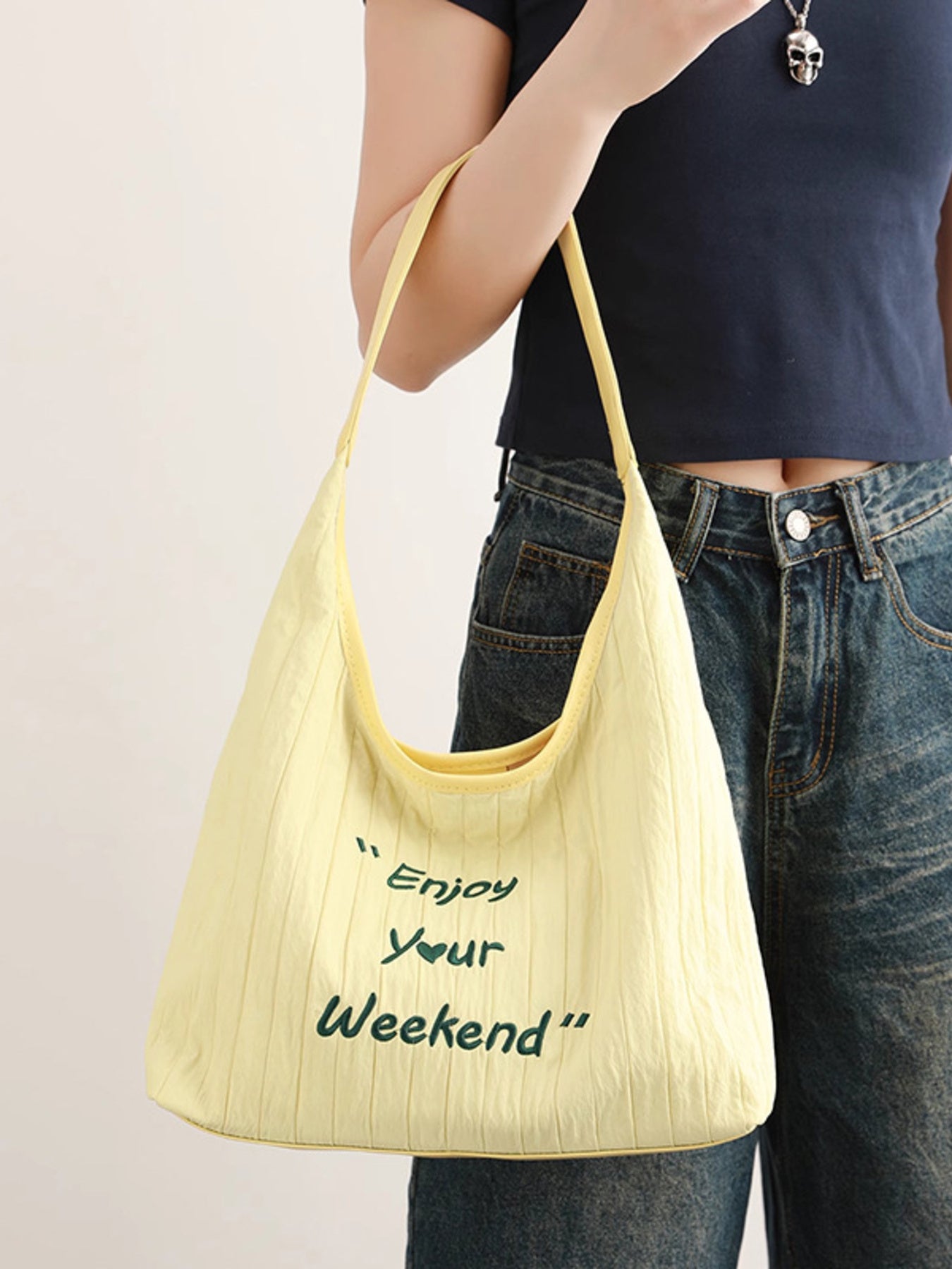 Person holding a yellow bag with 'Enjoy Your Weekend' text on a plain background