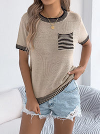 Woman wearing a beige short-sleeve top with black trim and denim shorts on a white background